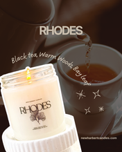 Load image into Gallery viewer, RHODES candle with a cup of tea on a dark background